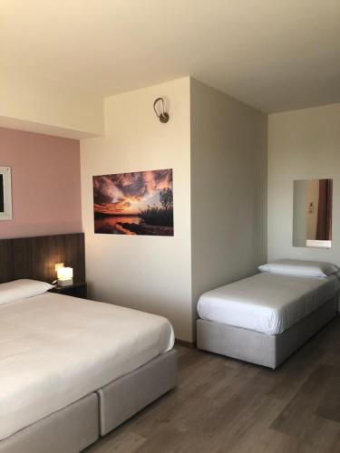 Prealpina Hotel في Bagnolo Piemonte: غرفة نوم بسريرين ولوحة على الحائط
