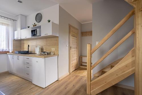 a kitchen with white cabinets and a wooden staircase at DOMKI NA WIERCHU in Biały Dunajec