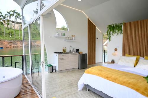 ein Schlafzimmer mit einem großen Bett, einer Badewanne und einem Waschbecken in der Unterkunft Casa Flotante La Trinidad in Guatapé