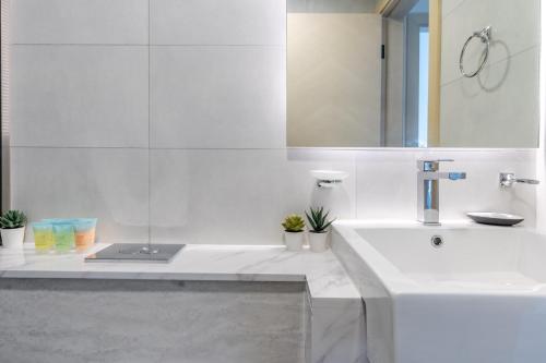 a white bathroom with a sink and a mirror at Apartment with City Skyline View Pool & Gym Access in Dubai