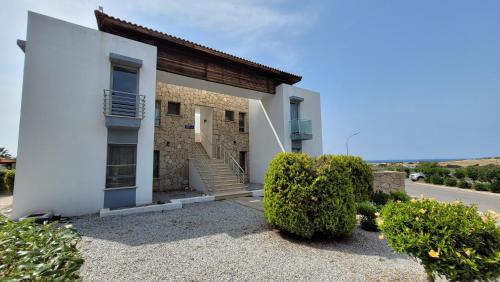 a white building with stairs and bushes in front of it at Sea and Mountain View Beachfront Penthouse in Yalı