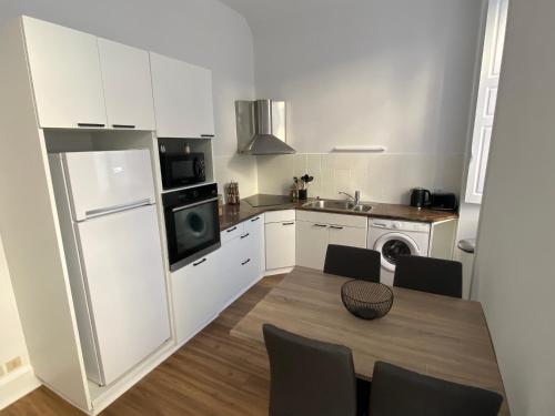 La cuisine est équipée d'une table, d'un réfrigérateur et d'un évier. dans l'établissement Appartement - 2 chambres - Parking voiture, à Mazamet