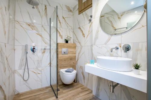 ein Badezimmer mit Waschbecken, Toilette und Spiegel in der Unterkunft Studios Passa in Limenaria