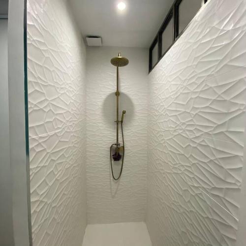 La salle de bains est pourvue d'une douche avec un mur blanc. dans l'établissement Jolie appartement en plein centre du village, aux Arcs-sur-Argens