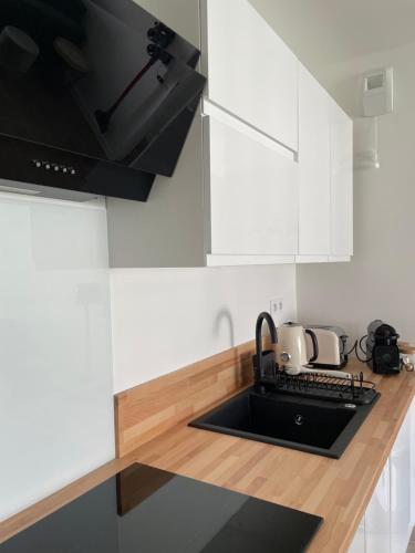 a kitchen with white cabinets and a sink at Disneyland-Paris - 5 pers Netflix, Parking, Wifi in Serris