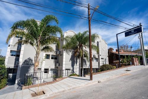 a white building with palm trees on a street at Nuevo Centro Hotel Villa Carlos Paz in Villa Carlos Paz