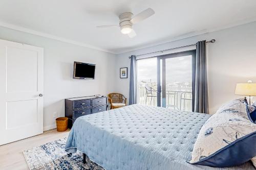 a white bedroom with a bed and a balcony at Bay Creek Villa - 304 in Edisto Island