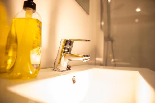a bathroom sink with a yellow soap bottle next to it at Apartamentos Lidar in Bilbao