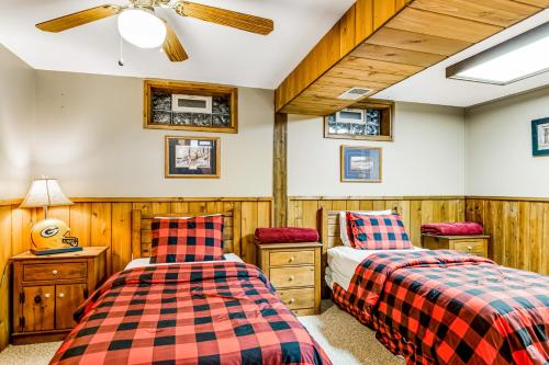 two beds in a room with wooden walls at Three Bears Lodge in Boulder Junction