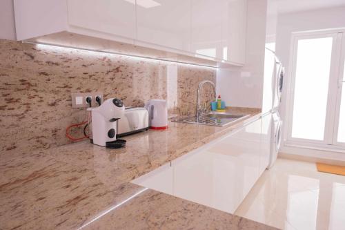 eine weiße Küche mit einem Waschbecken und einer Arbeitsplatte in der Unterkunft Luxury Apartments Sabi Waikiki con garaje in Corralejo