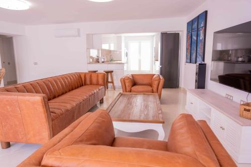 ein Wohnzimmer mit braunen Ledersofas und einem Fernseher in der Unterkunft Luxury Apartments Sabi Waikiki con garaje in Corralejo