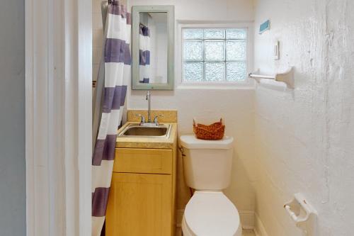 a bathroom with a toilet and a sink and a window at Shortboard in Holmes Beach