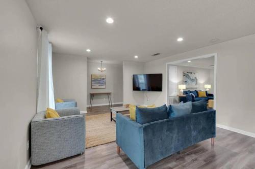 Sala de estar con 2 sofás azules y TV en Quiet relaxing home - Close to Downtown & Beach 4BR-2BT, en Pensacola