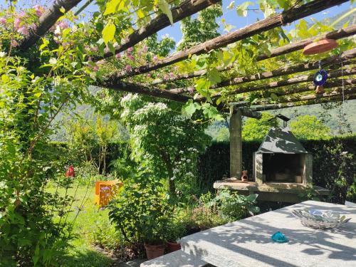 a garden with a pergola and a table with a stove at CASA ALLA CASCATA House by the Waterfall and Garden of Senses in Maggia