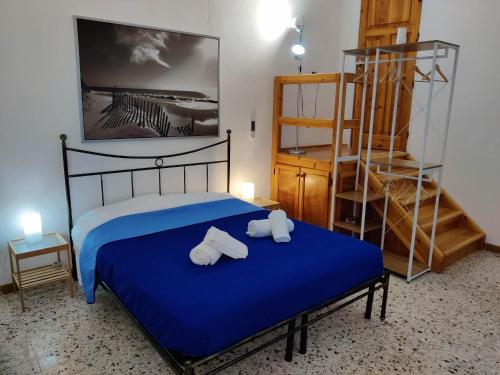 una camera da letto con un letto blu e asciugamani di Il Giardino su Lido Burrone a Favignana