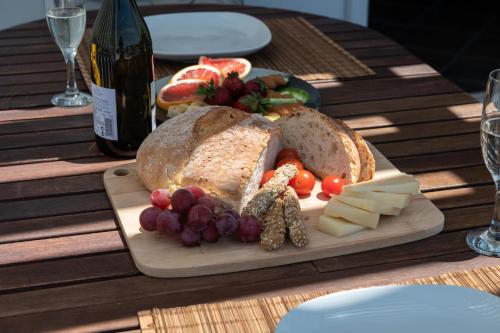 a cutting board with a loaf of bread and grapes and cheese at Sea Lilies Suites in Plaka