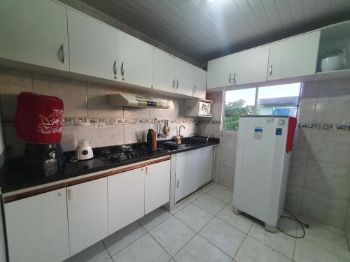 eine Küche mit weißen Schränken und einem weißen Kühlschrank in der Unterkunft Casa Praia São Jose Maragogi 4 in São José da Coroa Grande