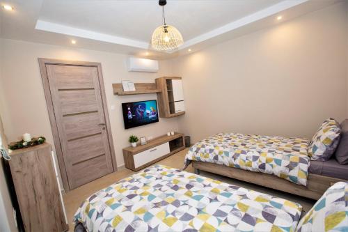 a small bedroom with two beds and a tv at Honeycomb Designer Apartment in St Paul's Bay