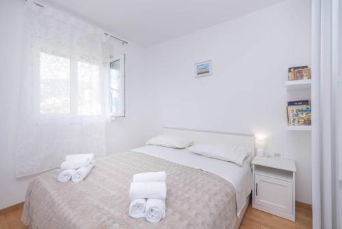 a white bedroom with a bed with two towels at Feel like Home in Podstrana
