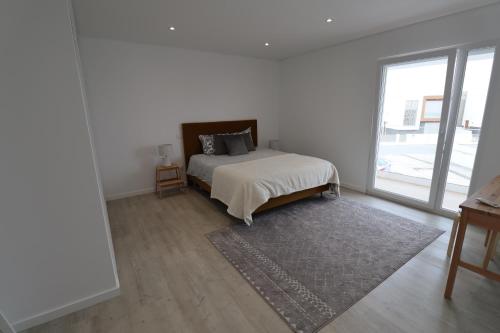 Dormitorio blanco con cama y ventana grande en T3 Euro Beach Life - Salir do Porto, en Salir de Porto
