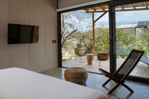 a bedroom with a view of a deck with a television at Eolia Sustainable Design Hotel in Manta