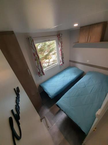 deux lits dans une petite pièce avec une fenêtre dans l'établissement L'échappée parisienne, à Saint-Chéron