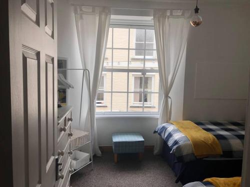 a small bedroom with a bed and a window at Seaton, Devon, two bed apartment, just off the sea front. in Seaton