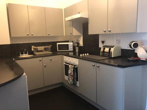 a kitchen with white cabinets and white appliances at Seaton, Devon, two bed apartment, just off the sea front. in Seaton