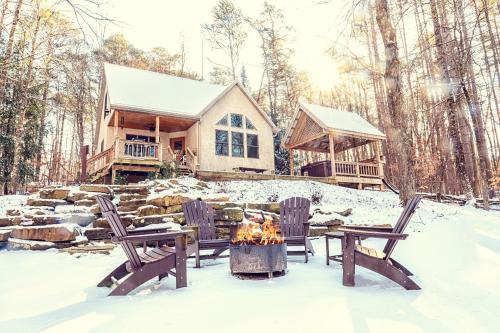a house in the snow with chairs and a fire pit at Cherry Ridge Retreat Luxury Cabins 