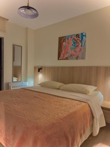Charming and Bright Tirana Center Apartament في تيرانا: غرفة نوم بسرير كبير عليها لوحة على الحائط