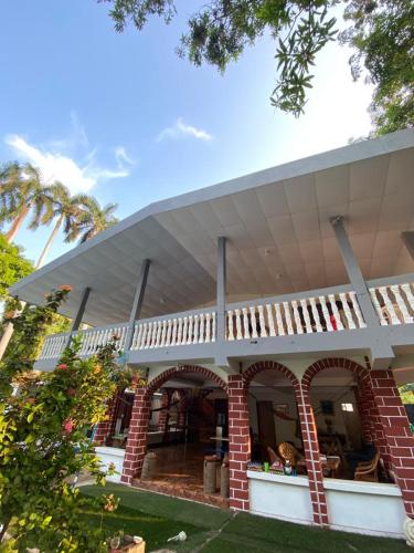 a house with a white roof and a brick at LA CASONA SV Hostal in La Libertad