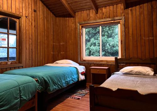 1 dormitorio con 2 camas en una cabaña de madera en Hostel del Valle, en Recinto