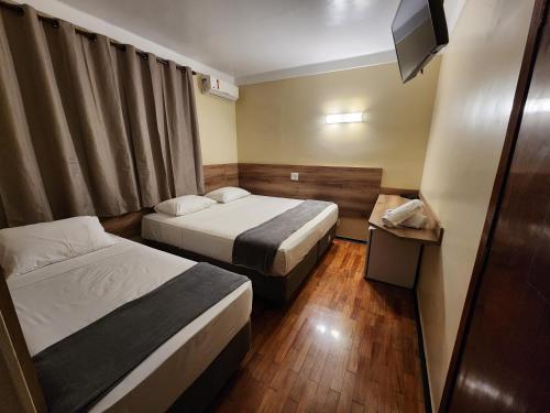 a hotel room with two beds and a television at Aurora Hotel in Ribeirão Preto