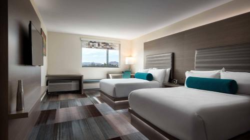 a hotel room with two beds and a tv at Aloft Scottsdale in Scottsdale