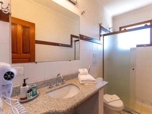 a bathroom with a sink and a toilet and a mirror at Hotel Velas do Engenho in Ilhabela
