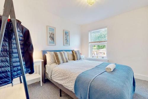 a bedroom with a blue bed and a window at Charming Victorian Terrace House Quick Walk to Station in Kent