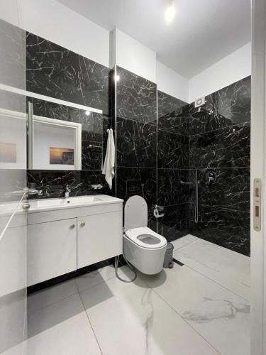 a black and white bathroom with a toilet and a sink at Hotel SEADEL in Ksamil