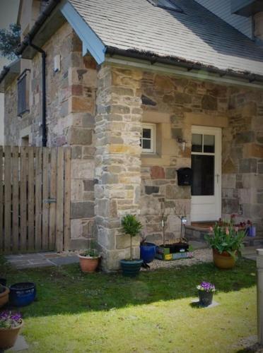 a stone house with potted plants in front of it at Loch Lomond Unique Selfcontained bed+bathroom in Alexandria
