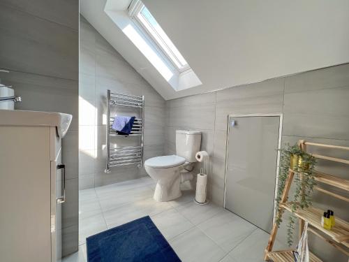 een witte badkamer met een toilet en een dakraam bij Heartland House, 7 Spacious Bedrooms Sleeps 4 plus, near NEC, JLR,BHX in Birmingham