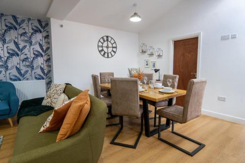 a dining room with a table and a green couch at Heartland House, 7 Spacious Bedrooms Sleeps 4 plus, near NEC, JLR,BHX in Birmingham