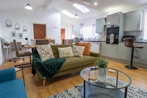 a living room with a green couch and a kitchen at Heartland House, 7 Spacious Bedrooms Sleeps 4 plus, near NEC, JLR,BHX in Birmingham