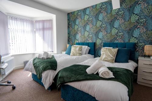 two beds in a bedroom with blue and green wallpaper at Heartland House, 7 Spacious Bedrooms Sleeps 4 plus, near NEC, JLR,BHX in Birmingham
