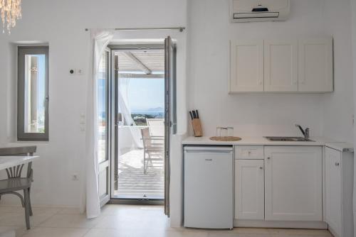 a kitchen with white cabinets and a view of the ocean at Aeraki Villas in Santa Maria