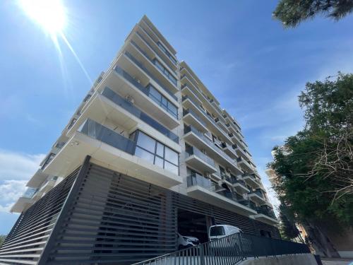 een hoog wit gebouw met de zon in de lucht bij LUXURY Residence Apartments in Mamaia