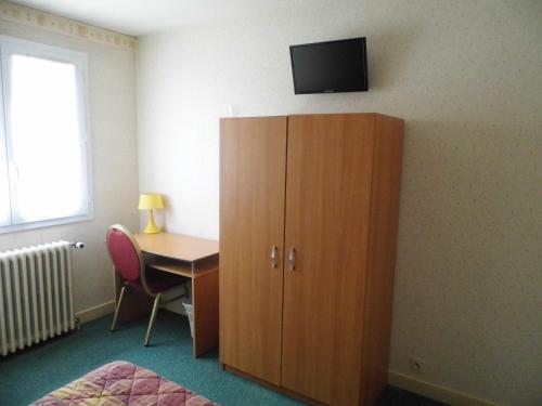 Habitación con escritorio y armario con TV en la pared. en A L'Orée du Bois, en Bellerive-sur-Allier