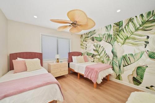 1 dormitorio con 2 camas y un mural de hojas en Luxury Beach House Oasis 3 Blocks from the Beach en Cape Canaveral
