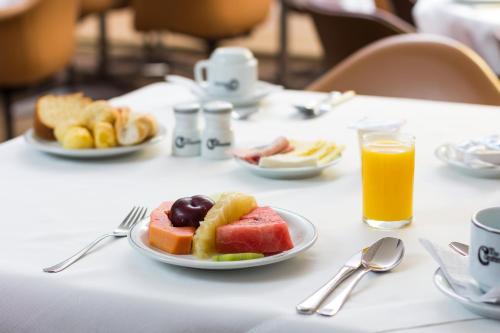 een tafel met een schaal fruit en sinaasappelsap bij América Bittar Hotel in Brasilia