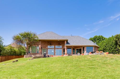 a house on a hill with a green lawn at Lakefront Little Elm Home with Private Pool! in Little Elm