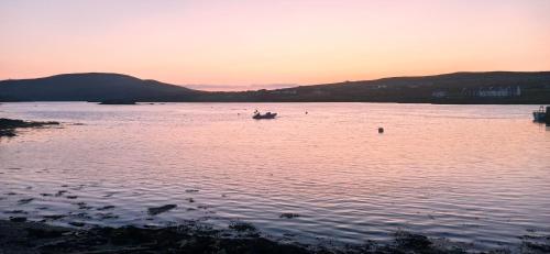 a boat in a large body of water at sunset at Portmagee Village Apartments in Portmagee