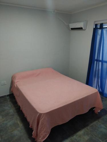 a bed in a room with a pink blanket on it at MAIPU Apart in Maipú